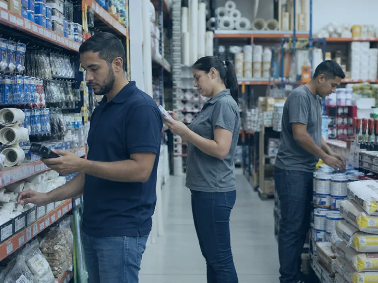 Three people are standing in a store aisle, examining products on shelves.