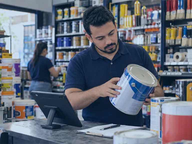 Funcionário conferindo lata de tinta durante processo de trocas e devoluções em loja de tintas